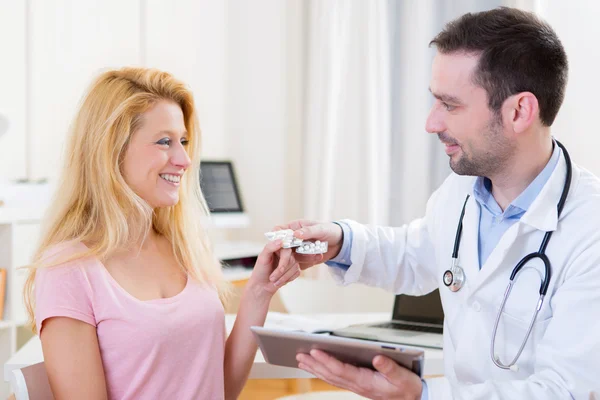 Молодой привлекательный врач дает таблетки пациенту — стоковое фото