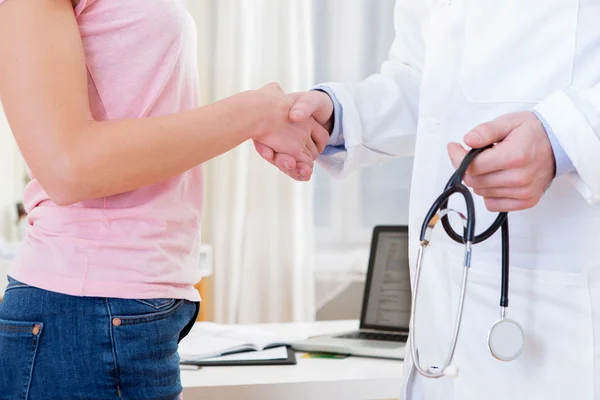 Young attractive doctor shaking hand of his patient