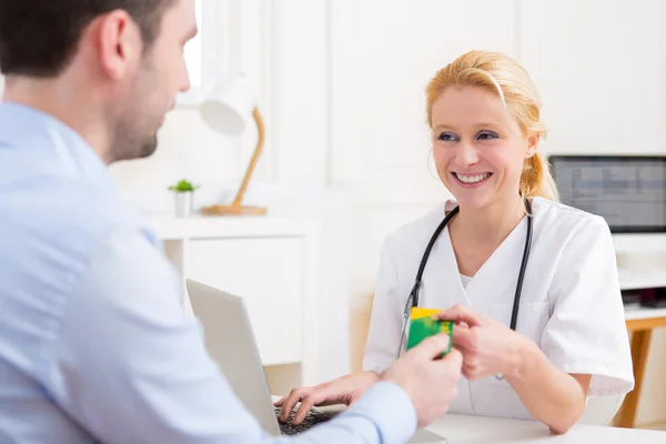 Jeune médecin attrayant prenant carte d'assurance maladie — Photo