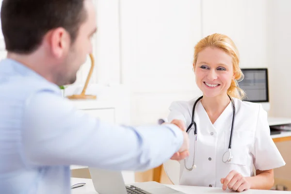 Junger attraktiver Arzt schüttelt seiner Patientin die Hand — Stockfoto