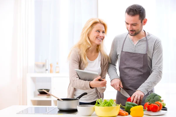 Jeune couple attrayant lecture recette sur une tablette — Photo