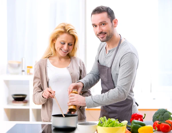 Young attractive man helping out his wife while cooking — Stock Photo, Image