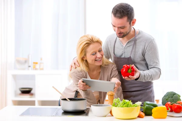 Young attractive couple reading recipe on a  tablet — Stock Photo, Image