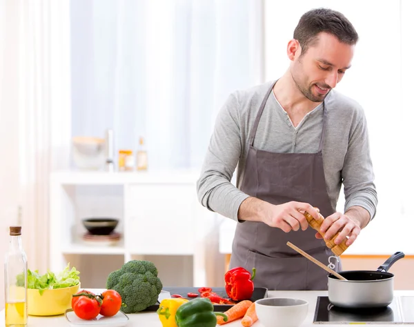 Young attractive man cooking in a kitchen — Stock Photo, Image