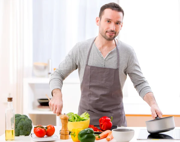 Jovem homem atraente cozinhar em uma cozinha — Fotografia de Stock