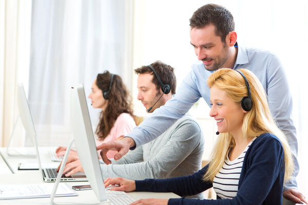 Manager training a young attractive people on computer