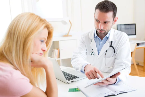 Médico jovem mostrando resultados em comprimido para paciente — Fotografia de Stock