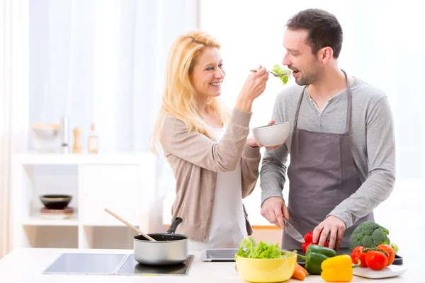 Young attractive woman give food to her husband to taste — Stock Photo, Image