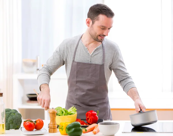 Junger attraktiver Mann kocht in einer Küche — Stockfoto