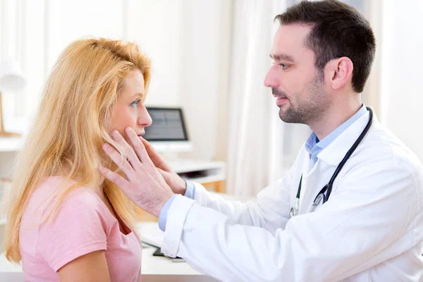 Young attractive doctor analysing blonde patient face — Stock Photo, Image