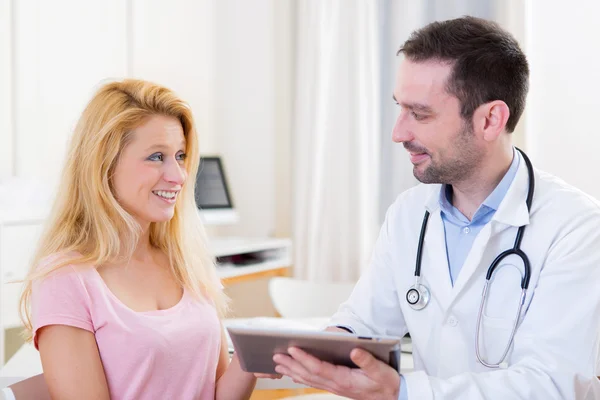 Médico jovem mostrando resultados em comprimido para paciente — Fotografia de Stock