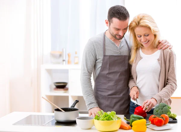 Jovem casal atraente cozinhar em uma cozinha — Fotografia de Stock