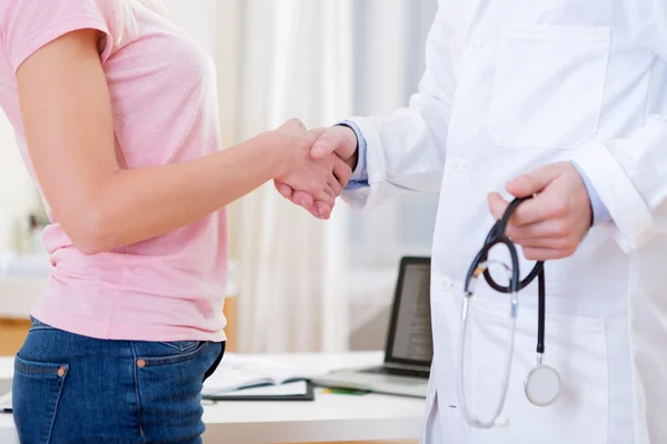 Junger attraktiver Arzt schüttelt seiner Patientin die Hand — Stockfoto