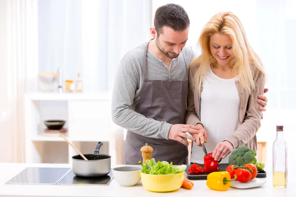 Jovem homem atraente ajudando sua esposa enquanto cozinha — Fotografia de Stock