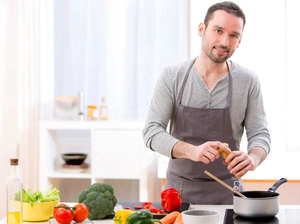 Jovem homem atraente cozinhar em uma cozinha — Fotografia de Stock