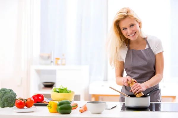 Junge attraktive Frau kocht in einer Küche — Stockfoto