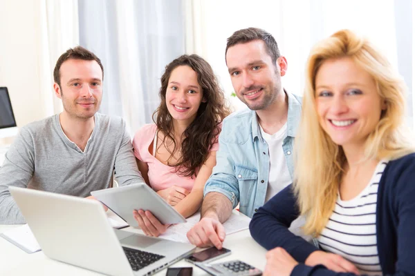 Gruppo di 4 giovani attraenti che lavorano su un computer portatile — Foto Stock