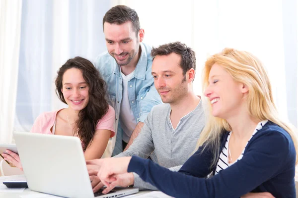 Grupo de 4 jóvenes atractivos trabajando en un ordenador portátil — Foto de Stock