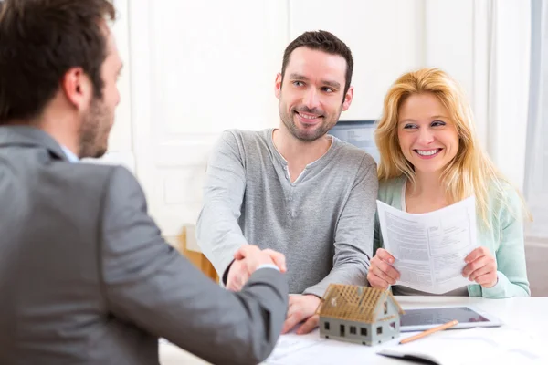 Young happy couple handshaking real estate agent after signing c — Stock Photo, Image