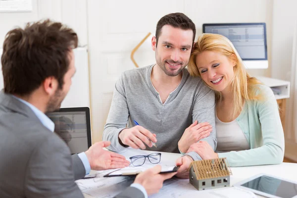 Jonge aantrekkelijke paar ondertekening contract met onroerende goederenagent — Stockfoto