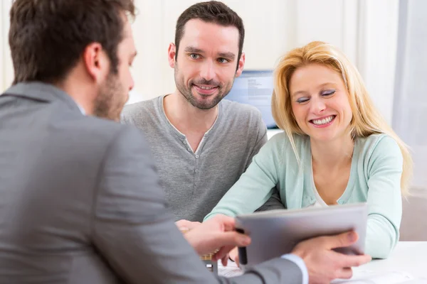 Real estate agent present project on tablet to a young couple — Stock Photo, Image