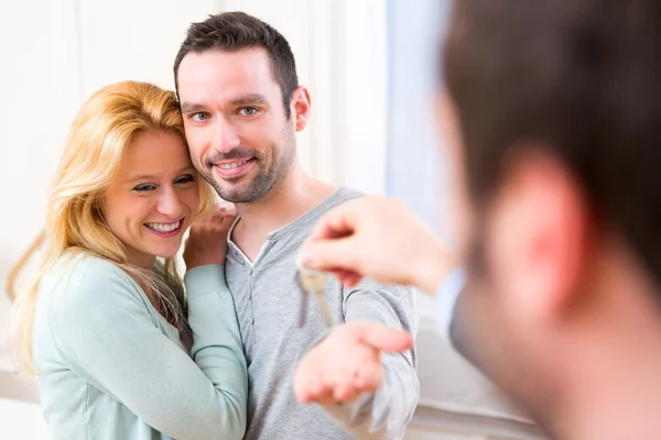 Onroerende goederenagent levert sleutels van nieuw huis aan jong koppel — Stockfoto