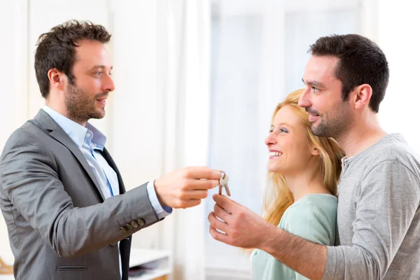 Immobilienmakler übergibt Schlüssel für neues Haus an junges Paar — Stockfoto