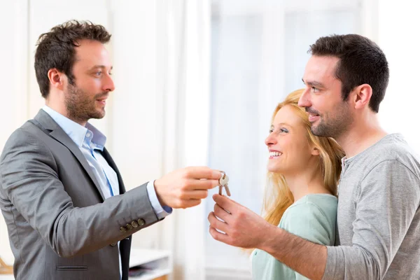 Real estate agent delivers keys of new house to young couple — Stock Photo, Image