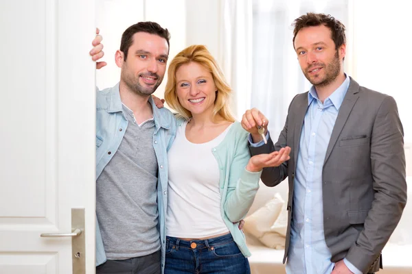 Real estate agent delivers keys of new house to young couple — Stock Photo, Image