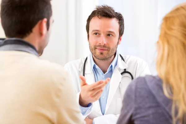 Young attractive doctor advising a young couple of patients — Stock Photo, Image