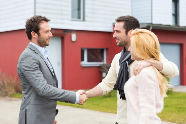 Real estate agent delivers keys to young atractive couple — Stock Photo, Image