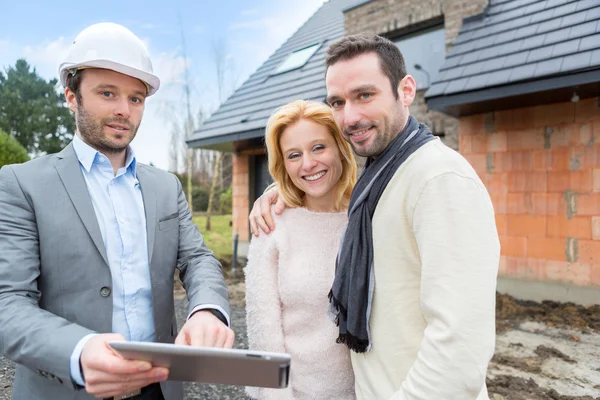 Real estate agent and a young couple in front of future home — Stock Photo, Image