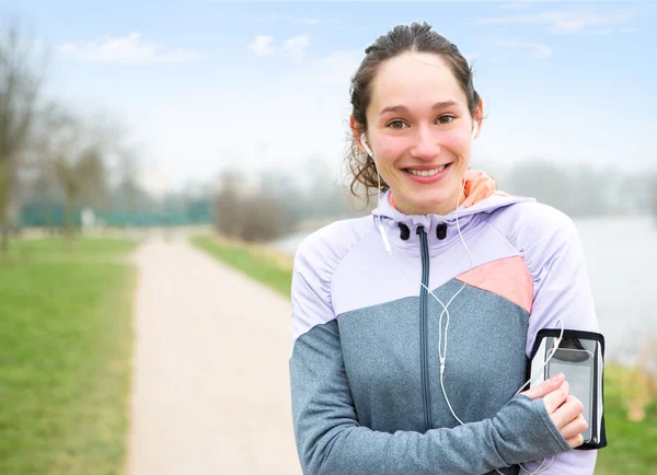 Junge attraktive Frau passt ihren Musikspieler vor dem Laufen an — Stockfoto