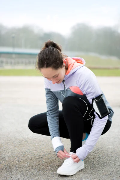Young attractive woman tying shoelaces before a running session — Stock Photo, Image