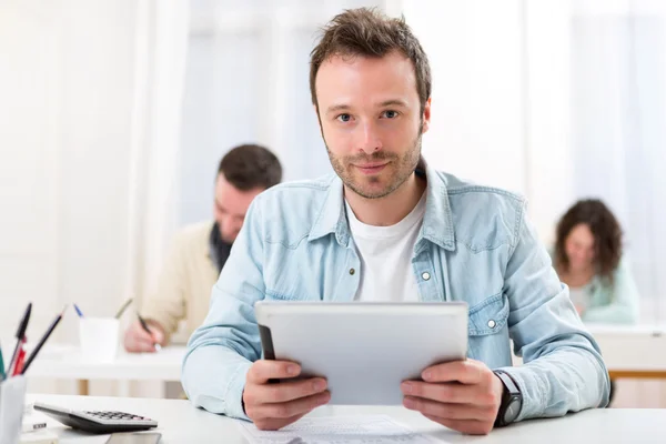 Jeune étudiant attrayant utilisant sa tablette pendant les cours — Photo