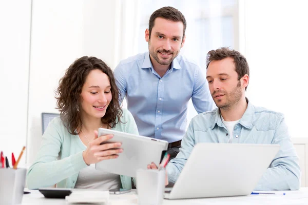 Dos pasantes trabajando juntos asistidos por su supervisor del curso — Foto de Stock