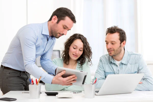 Dos pasantes trabajando juntos asistidos por su supervisor del curso — Foto de Stock