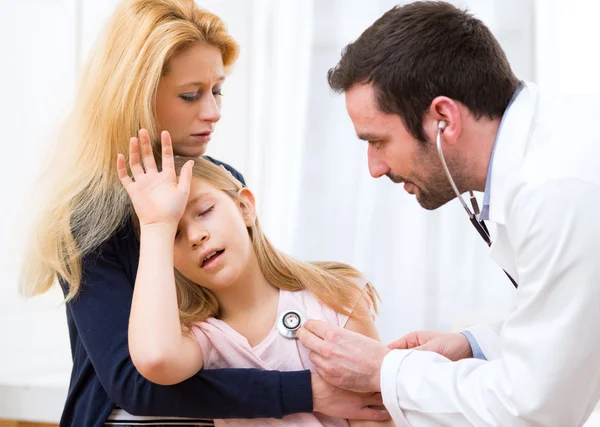 Доктор, слушающий биение сердца маленькой девочки — стоковое фото