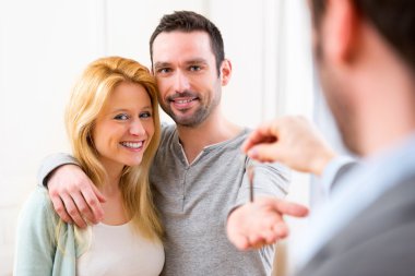 Emlakçı yeni ev anahtarları için genç çift sunar.