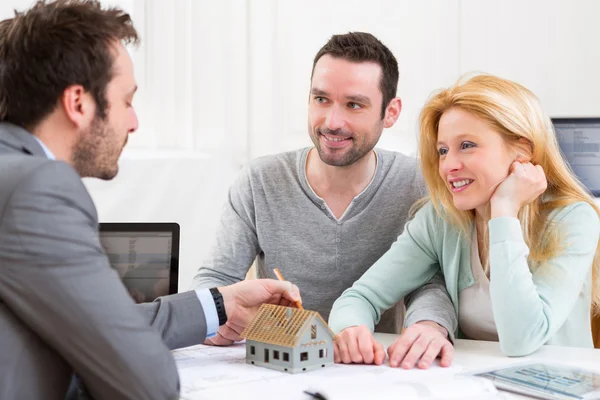 Real estate agent present project on miniature house to a young — Stock Photo, Image