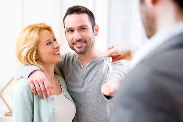 Onroerende goederenagent levert sleutels van nieuw huis aan jong koppel — Stockfoto