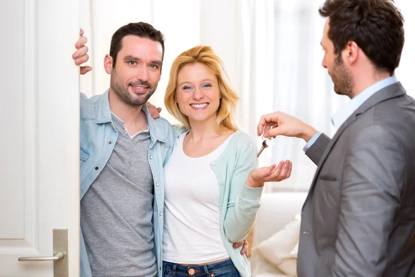 Agente imobiliário entrega chaves de casa nova para jovem casal — Fotografia de Stock