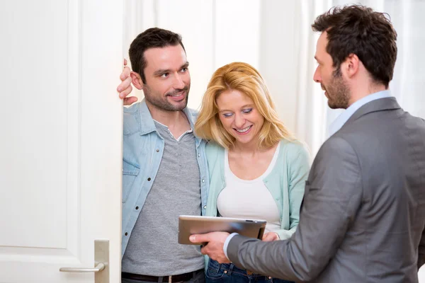 Agente imobiliário presente projeto em tablet para um jovem casal — Fotografia de Stock