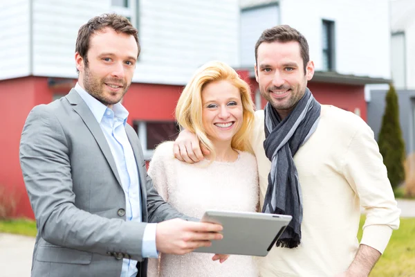 Real estate agent and a young couple in front of their next home — Stock Photo, Image