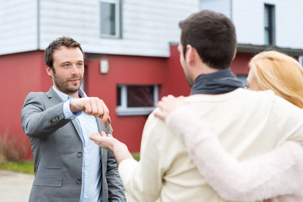 Real estate agent delivers keys to young atractive couple — Stock Photo, Image