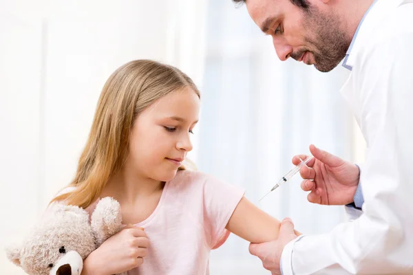 Niña joven siendo vacunada en el médico — Foto de Stock