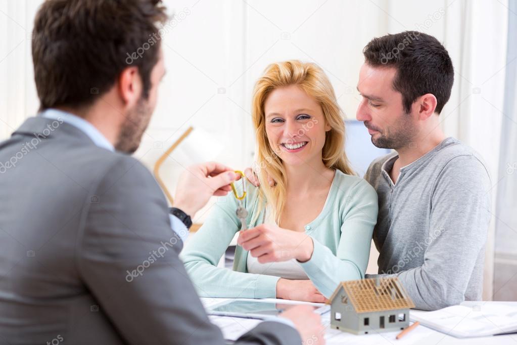 Real estate agent delivers keys of new house to young couple