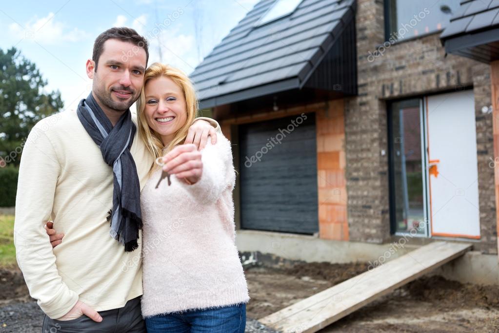 Young happy couple in front of their future house