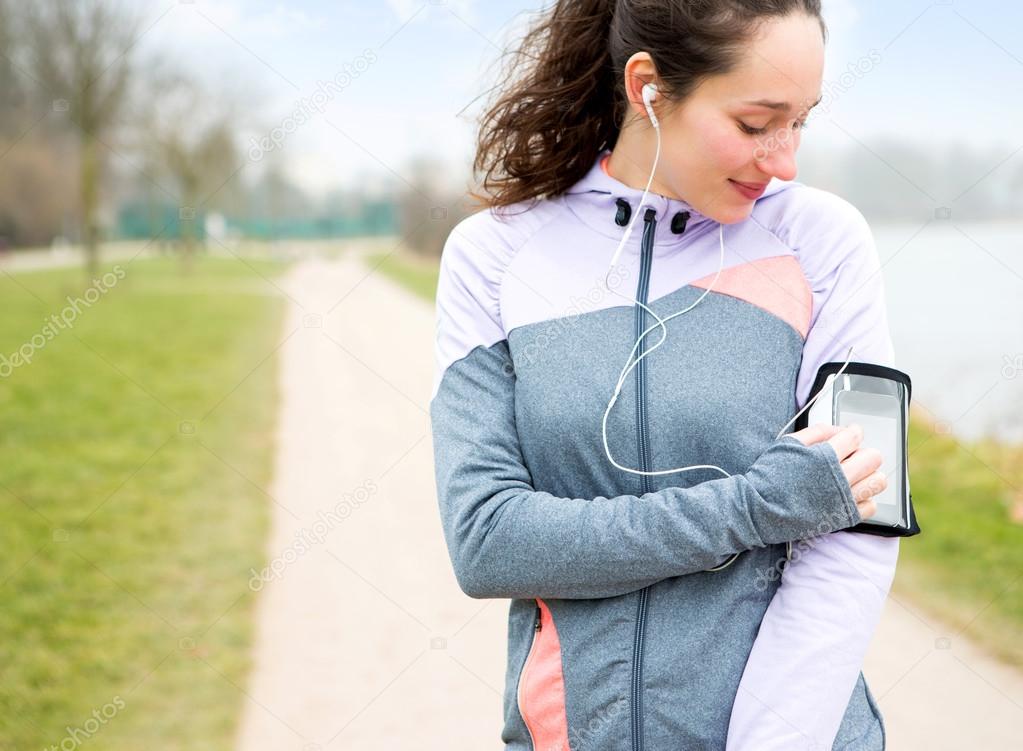 Young attractive woman adjust her music player before running