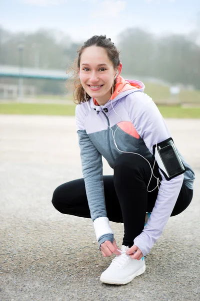 Junge attraktive Frau bindet Schnürsenkel vor einer Laufeinheit — Stockfoto